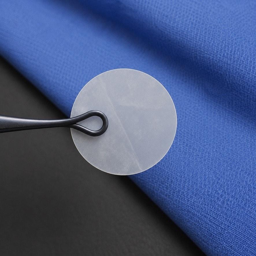 Eclipse amniotic membrane disc held by forceps on blue surgical drape